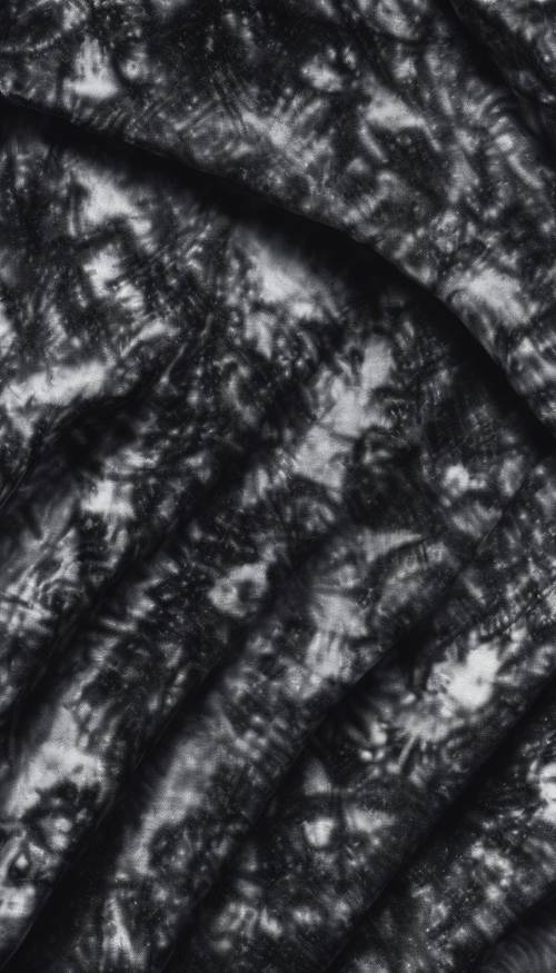 Tecido tie-dye preto com um padrão abstrato se espalhando.