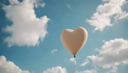 Balon berbentuk hati berwarna krem ​​​​mengambang di langit biru cerah.
