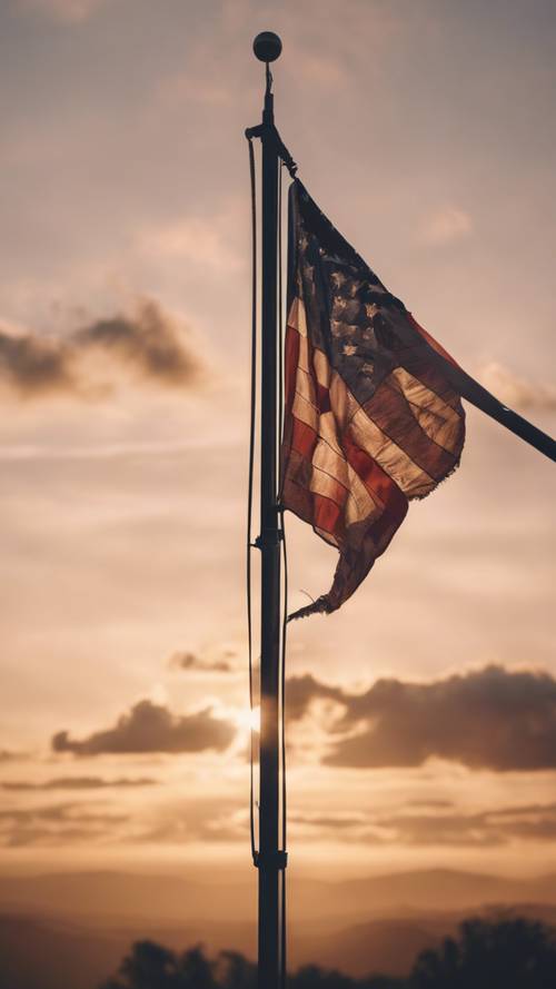 Un paesaggio al tramonto con una bandiera americana issata su un alto palo a fuoco