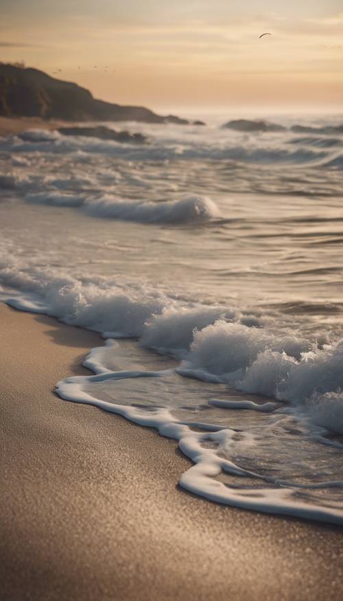 Eine bezaubernde Küstenszene im Morgengrauen mit Wellen, die sanft an das Sandufer plätschern.
