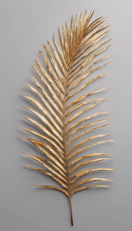 A simple yet elegant flat lay of a golden palm leaf on a light grey background.