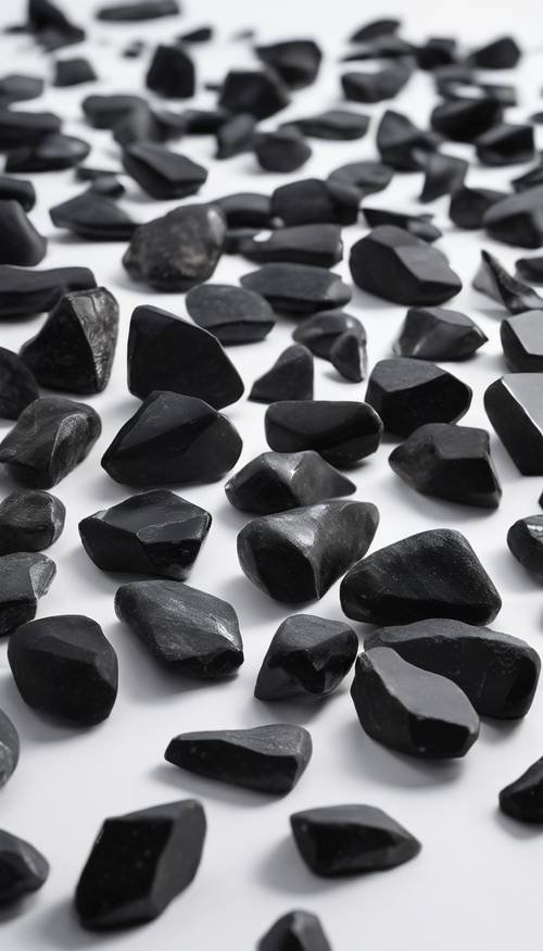 مجموعة من الحجارة السوداء المسننة المتناثرة على سطح أبيض نظيف.
