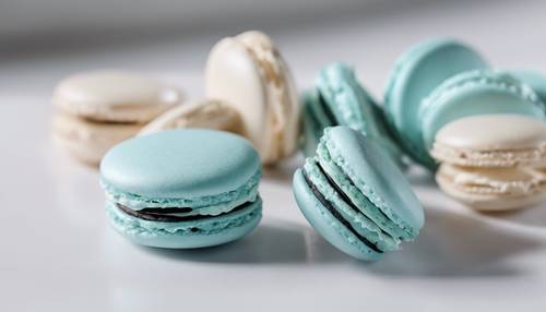 Un primer plano de delicados macarons de color azul celeste dispuestos sobre una mesa blanca minimalista.