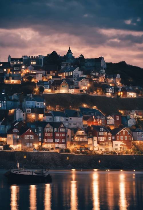 Un pueblo costero iluminado contra un cielo crepuscular de color azul oscuro