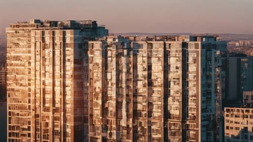 A cityscape bathed in early morning light, high-rise buildings casting long shadows, and the dawn sky mirrored in windows. Tapeta [84c472ed3b4149e9bb74]