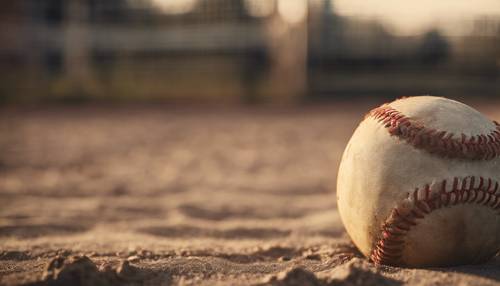 Ein alter, abgenutzter Softball in der rechten Ecke mit der untergehenden Sonne des Spätnachmittags im Hintergrund.