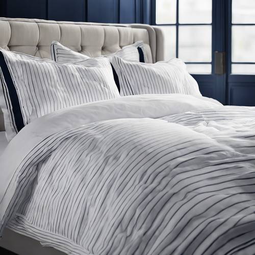 Un set di biancheria da letto bianco candido, decorato con sottili e moderne strisce blu navy.