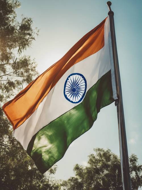 An Indian flag waving in the wind against a clear, bright blue sky.