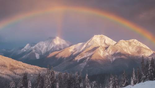 Magnificent view of white mountain peaks under a neutral colored rainbow at sunset.