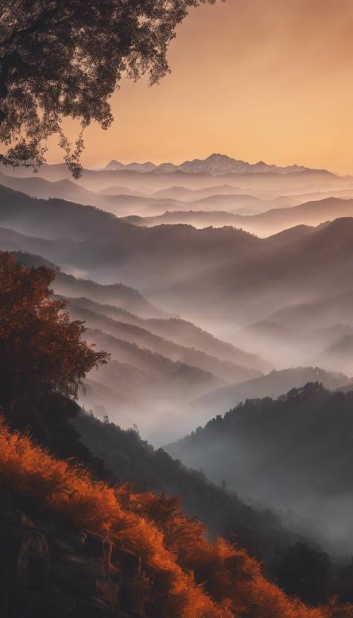 An orange sunrise illuminating a misty mountain range