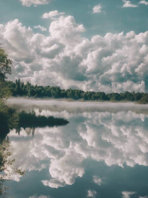 A dreamy shot of floating white clouds mirrored perfectly on a serene lake