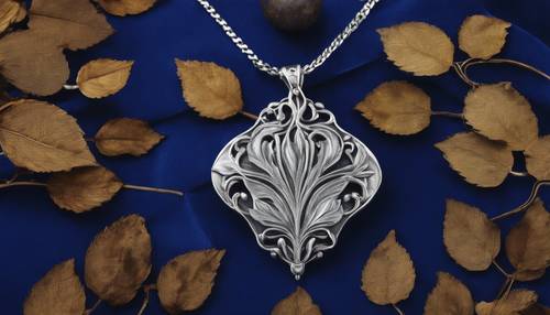 Inspirowany stylem secesyjnym srebrny wisiorek w kształcie liścia na tle królewskiego niebieskiego aksamitu.