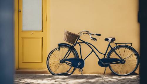 Una bicicletta vintage blu navy appoggiata a un muro giallo illuminato dal sole