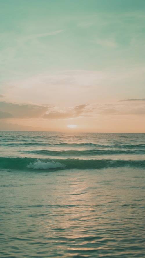 Ein ruhiger Blick auf ein pastellgrünes Meer, das während der goldenen Stunde auf einen mintfarbenen Himmel trifft.