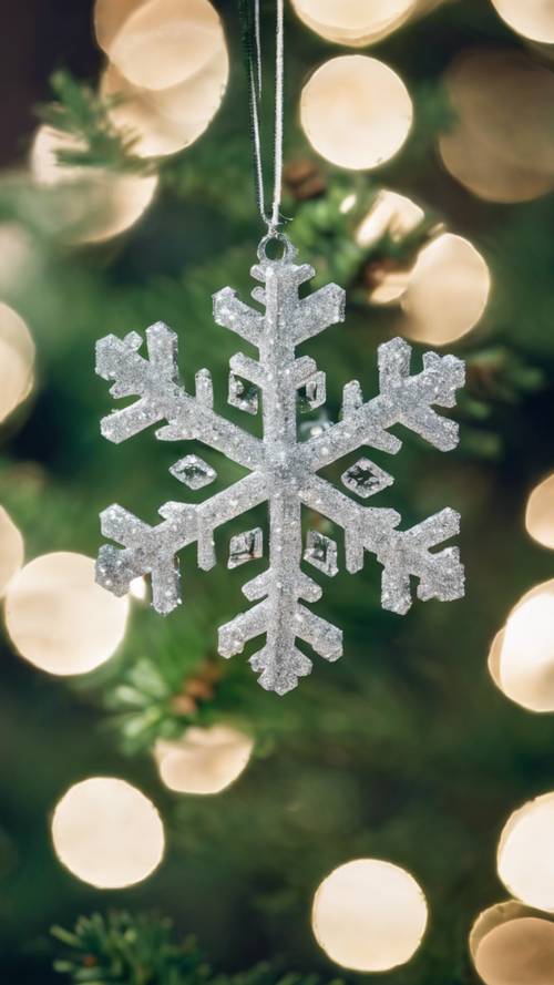 A snowflake-shaped Christmas ornament adorned with white glitter on a green pine tree