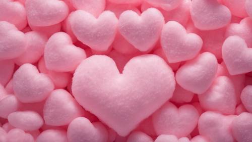 A soft pink heart made out of cotton candy at a vibrant fair.
