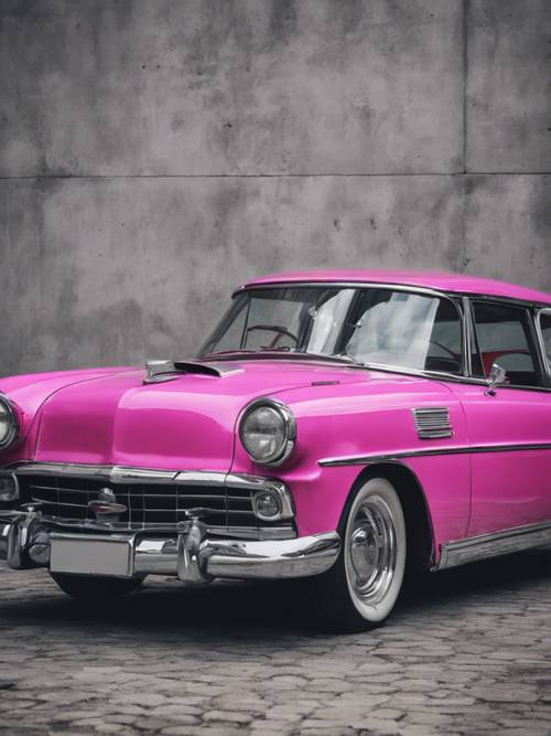 Ein klassischer Oldtimer in glänzendem Pink, der vor einer kühlen grauen Betonwand geparkt ist.