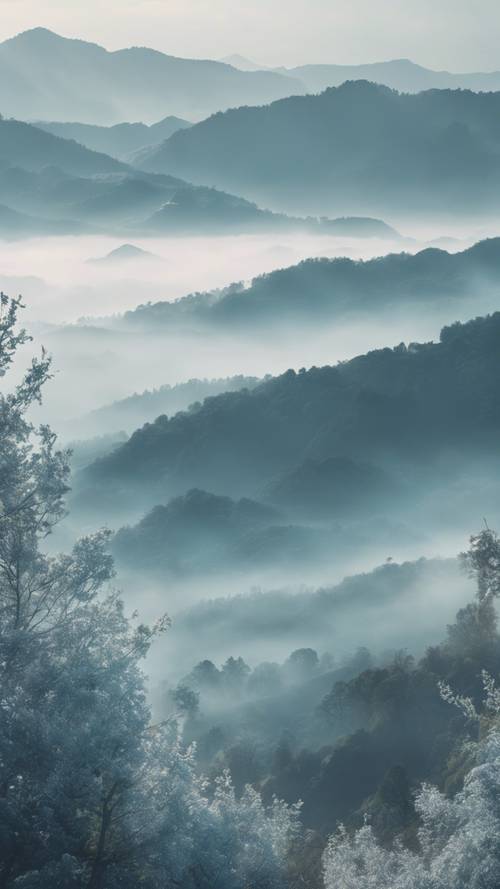 Pemandangan pagi hari yang menampilkan rona biru pastel pegunungan berkabut.