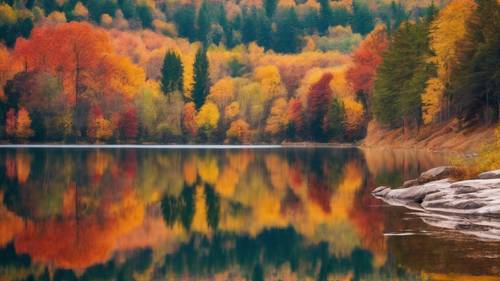 An autumn landscape with mirror-like lake reflecting colorful fall foliage.