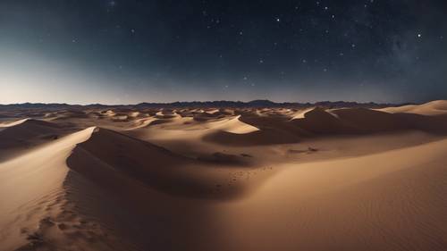 Downhill view of a desert valley, filled with a myriad of sand dunes under a clear night sky with stars.