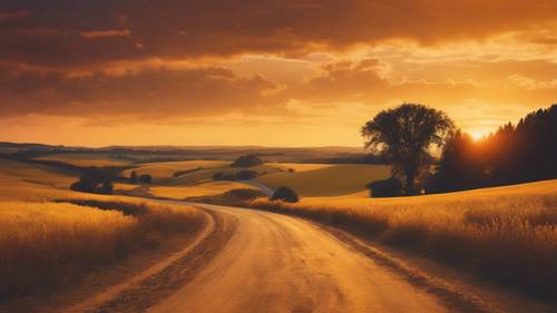 A winding road leading through golden fields under a vibrant, yellow-orange sunset.