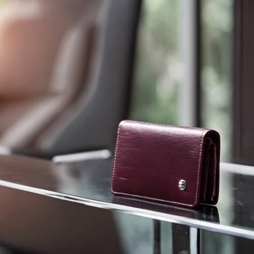 A cool maroon wallet with a silver clasp lying on a glass table.