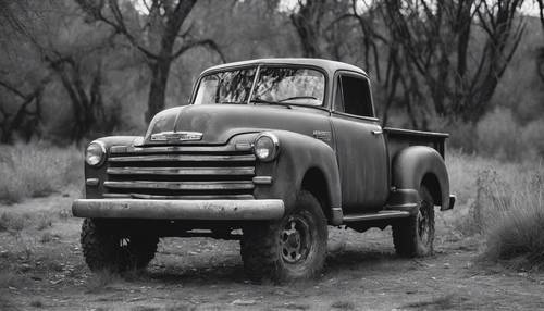 Une image de style film en noir et blanc d’une camionnette Chevrolet rustique argentée.