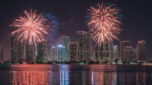 A festive Fourth of July fireworks display over the Miami skyline, with reflections in the water.