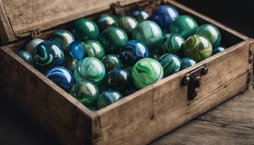 A vintage collection of cool marbles in all shades of green and blue stored in an old wooden box