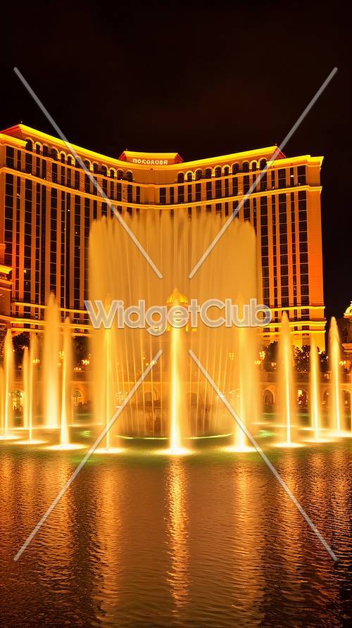 Le fontane danzano davanti a un hotel luminoso di notte