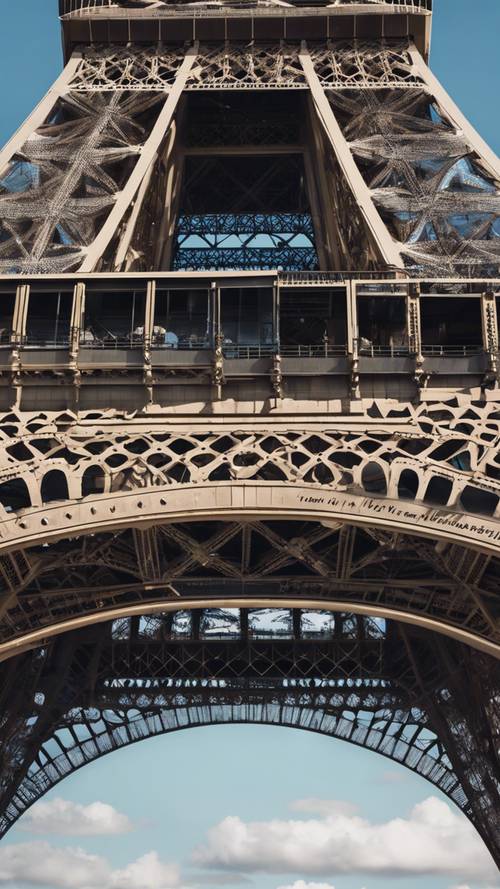 Um close-up da treliça da Torre Eiffel com o céu azul aparecendo.