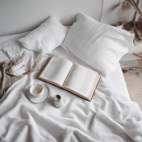 มุมมองทางอากาศของห้องนอนสีขาวล้วนสไตล์มินิมอลพร้อมผ้าห่มแสนสบายและหนังสือเล่มหนึ่งบนเตียง