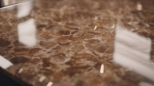 A close-up shot of a brown marble counter with soft lighting reflecting off the surface. Tapet [8cff28eb3bfc4d90b4d6]