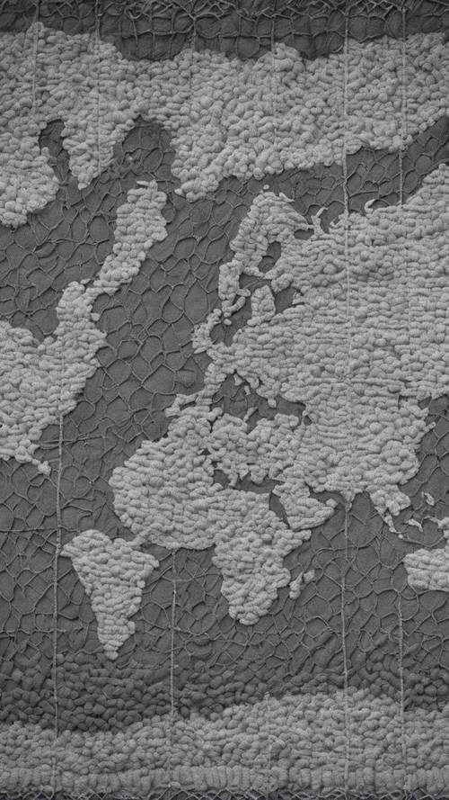 A grayscale world map knitted with different shades of gray wool on a blanket.