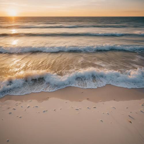 An aerial shot of a white sandy beach meeting the gold hues of the sunset.