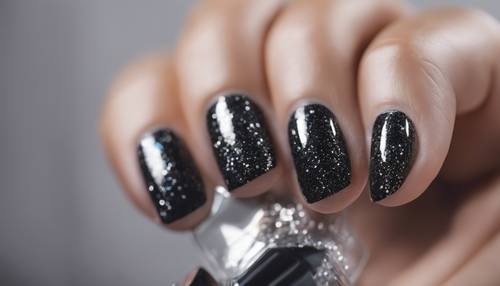 Uma luxuosa manicure com glitter preto e prateado.