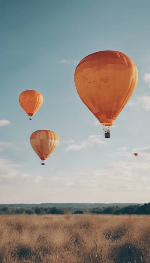 Tres globos aerostáticos de colores brillantes, naranja y blanco, volando en el cielo azul claro.