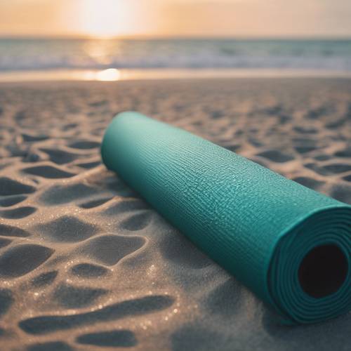 Matras yoga berwarna teal metalik tergeletak di pantai yang tenang saat fajar menyingsing.