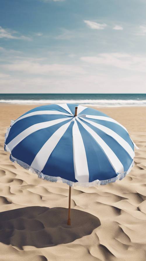 一把超大的藍白條紋沙灘傘，在晴空萬裡的沙灘上。