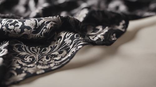 A piece of black damask fabric flowing in the wind on a neutral background.