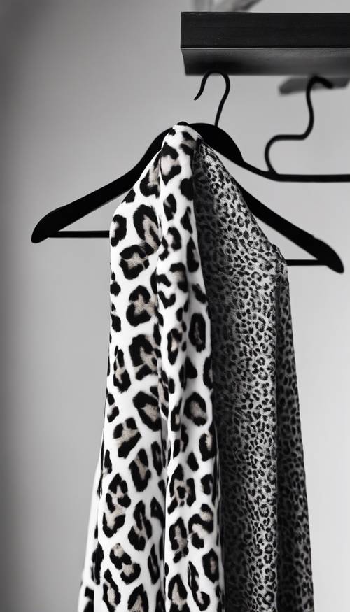 Black and white leopard print fabric draped softly across a wooden hanger. Валлпапер [5b244fa1df4f475c85f4]