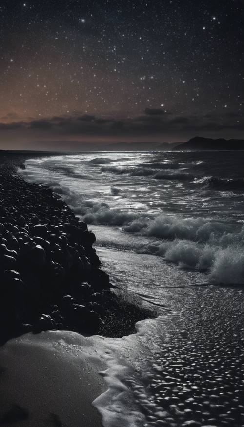A black beach with waves of dark water lapping at the shore under a starlit sky.