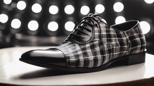 An Oxford shoe with a black and white plaid design, glistening under a spotlight.