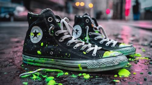 Um par de tênis Converse pretos respingados de tinta neon, espalhados descuidadamente na calçada.