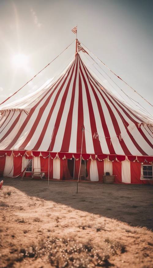 Una toma de gran angular de una carpa de circo bien decorada con vibrantes rayas rojas y blancas bajo la luz del sol de la tarde.