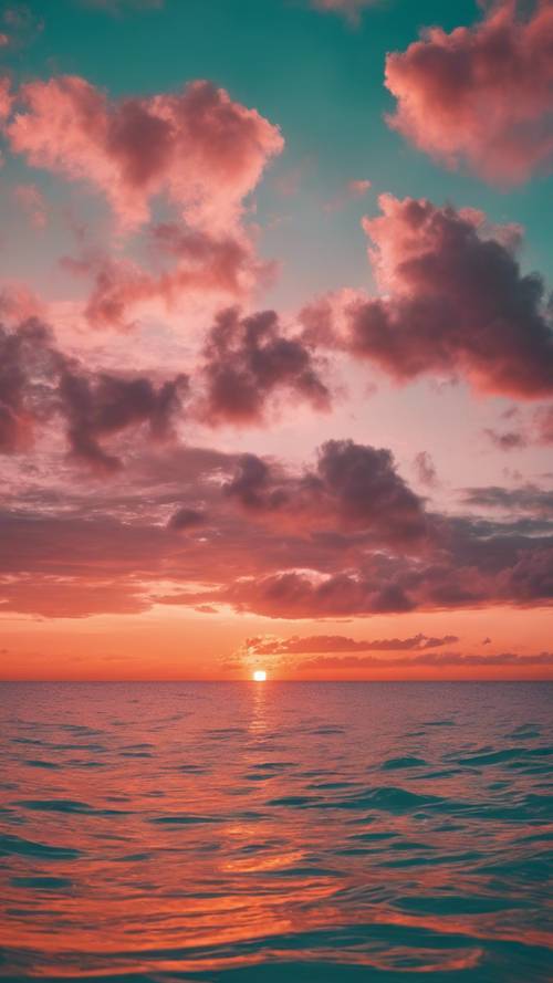 Matahari terbenam berwarna oranye dan merah muda yang cerah di atas lautan biru kehijauan yang tenang