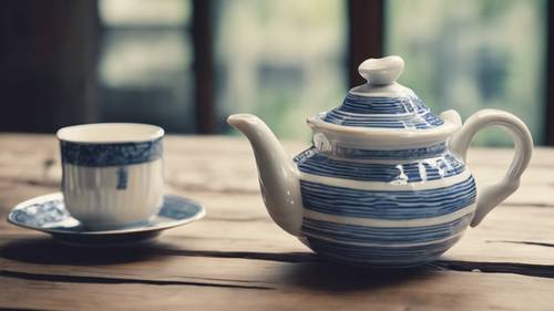 إبريق شاي بورسلين عتيق مخطط باللونين الأزرق والأبيض على طاولة خشبية.